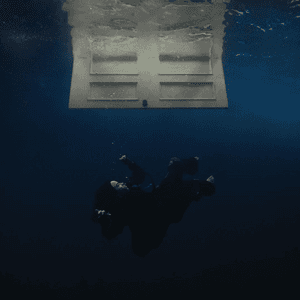 An underwater image of a body sinking below a blue-lit surface